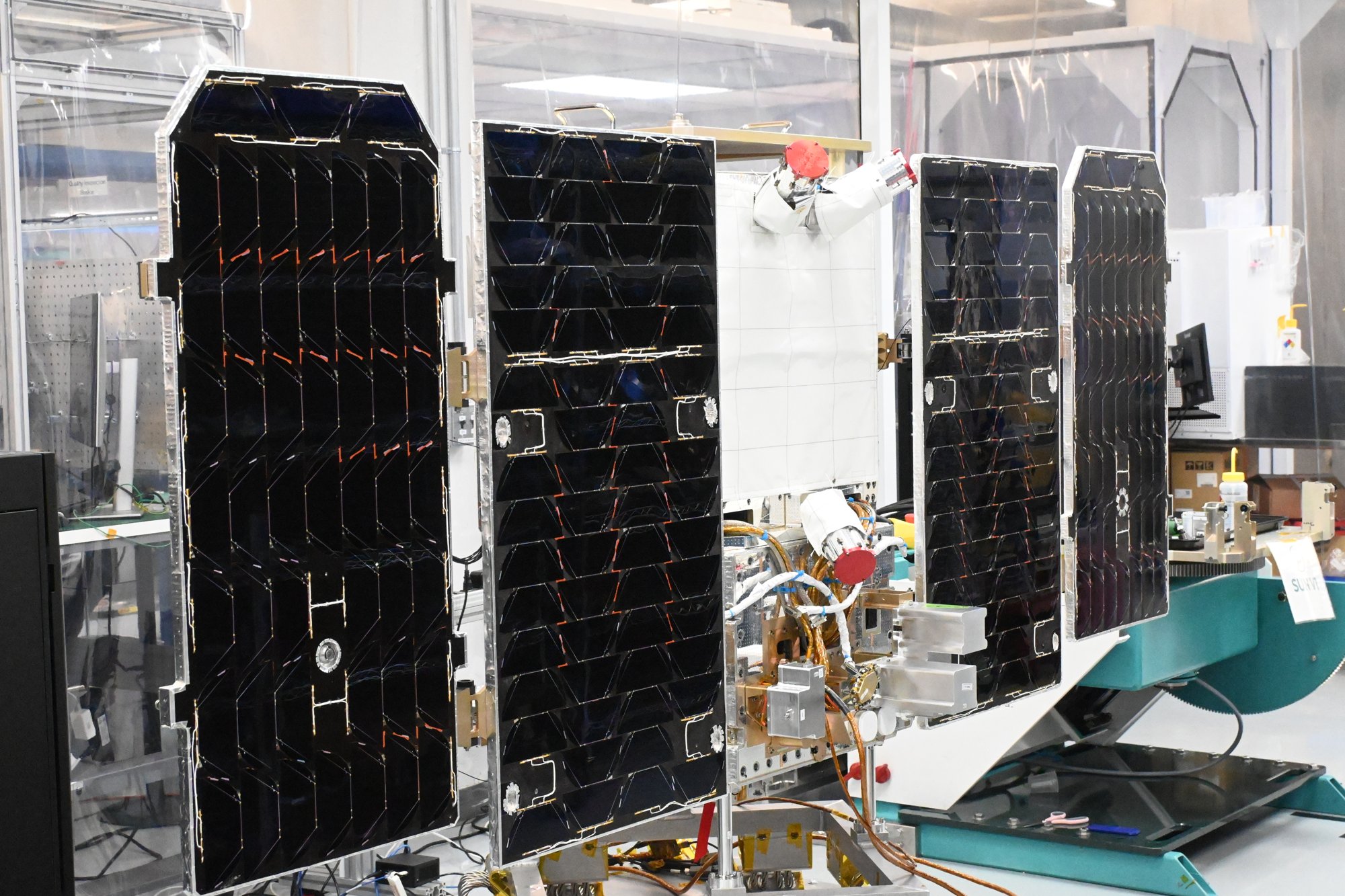 The Project Suncatcher prototype satellite with its four black solar wings unfolded, in a Planet cleanroom